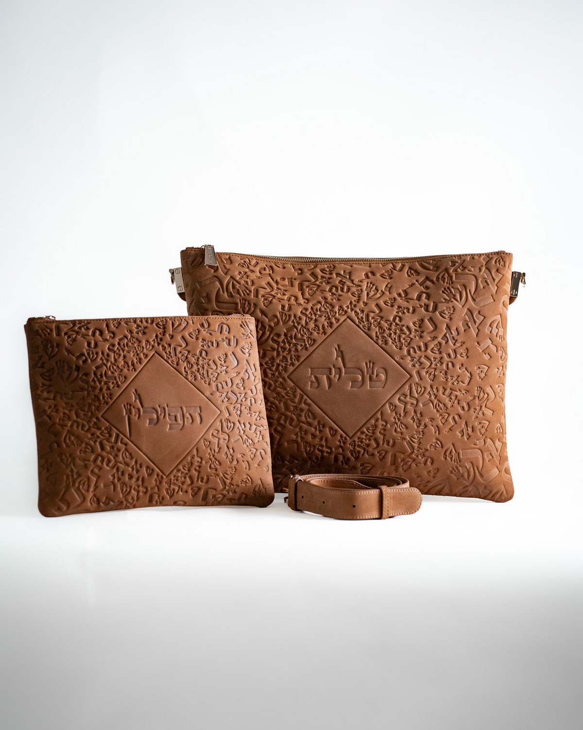 Light brown leather tallit bag and tefillin bag with a strap on white