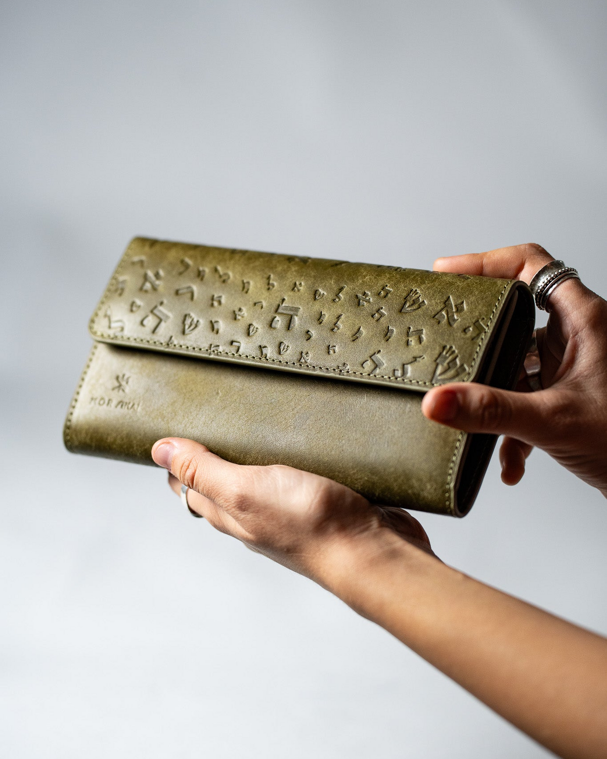 Olive green leather ladies wallet with embossed Israel Letters held in a hand