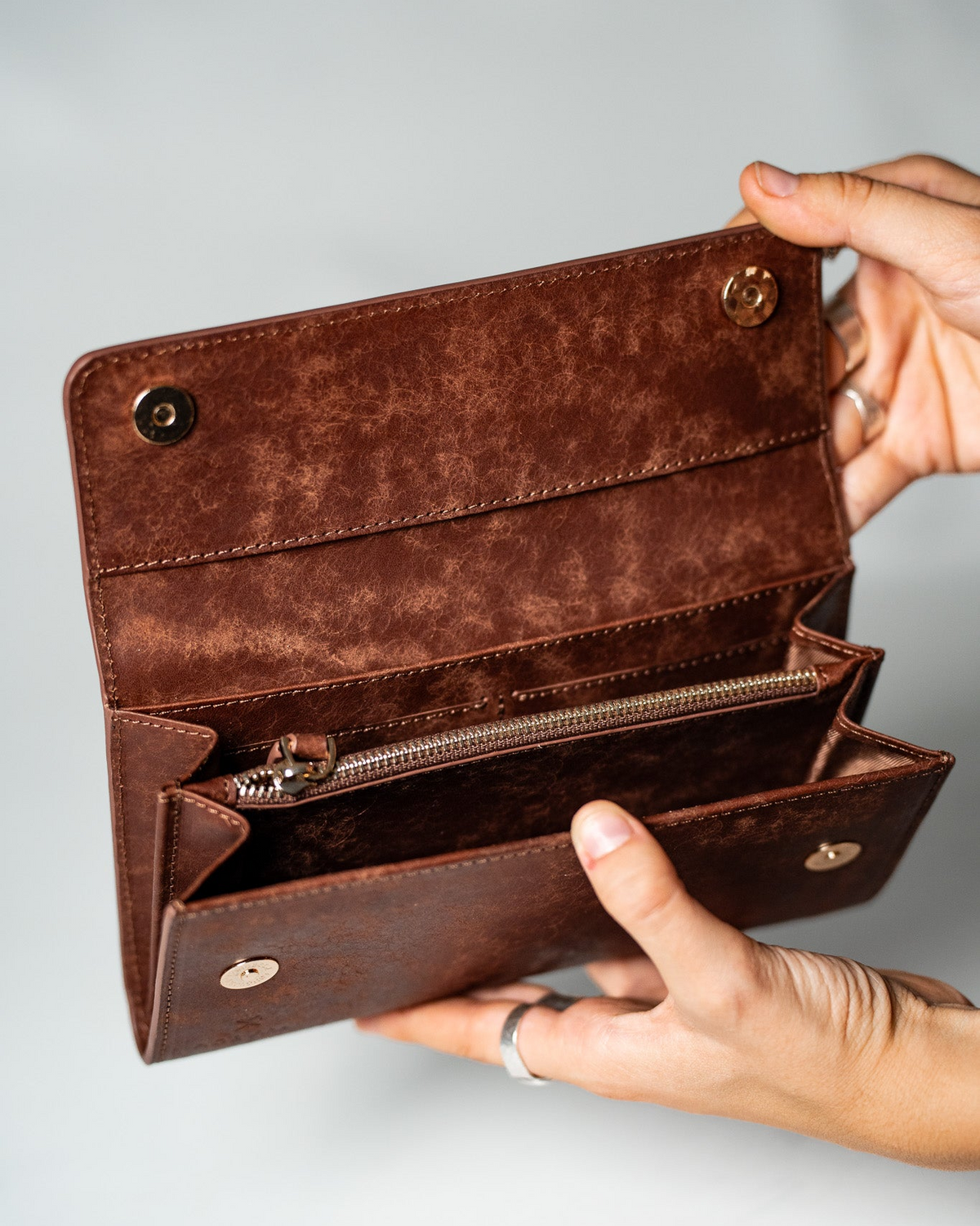 Hands opening the brown leather ladies wallet to show the interior