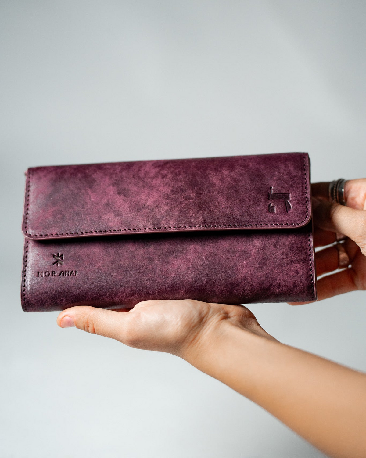 Burgundy leather ladies wallet held in a hand, closed