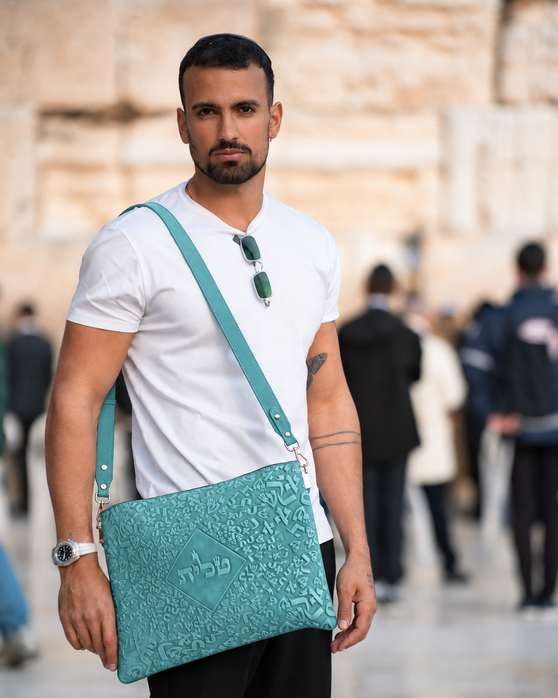Man in a white shirt wearing the turquoise leather tallit bag across his body