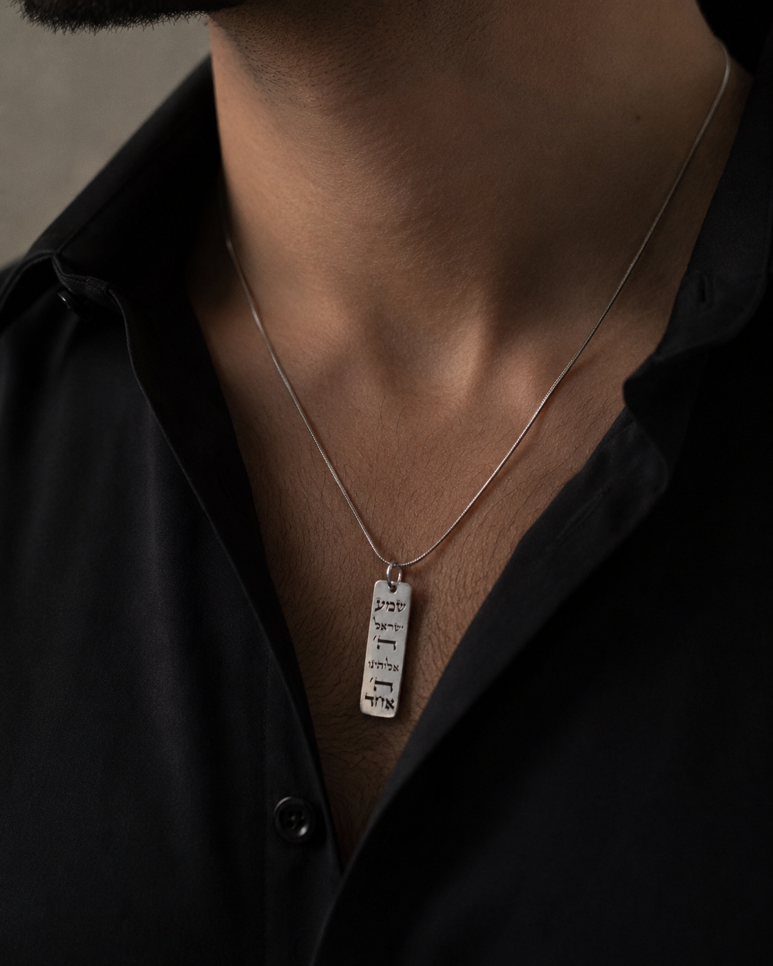 Man wearing a slim 925 silver pendant on a chain with a black shirt