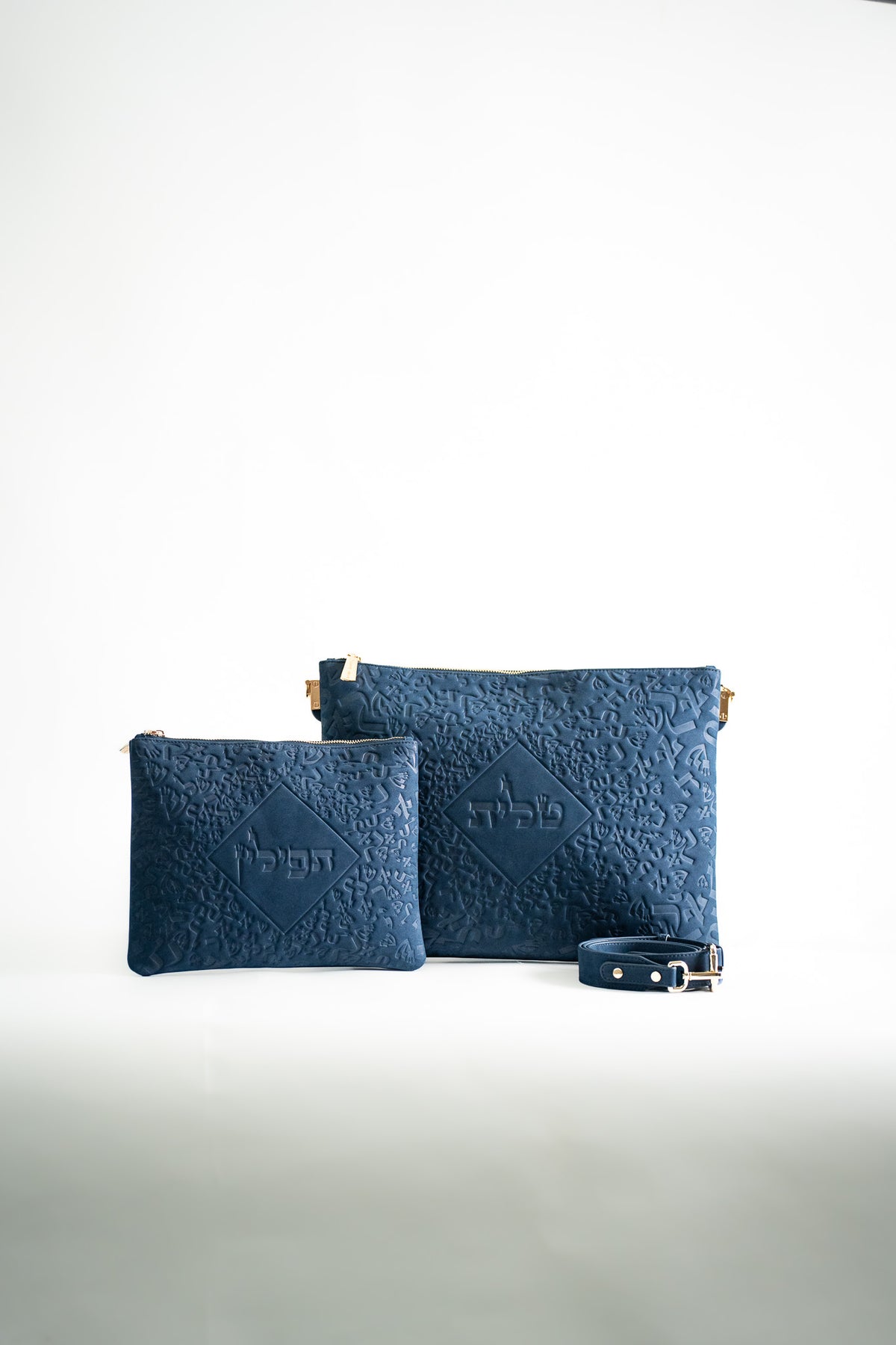 Blue leather tallit bag and tefillin bag side by side on white