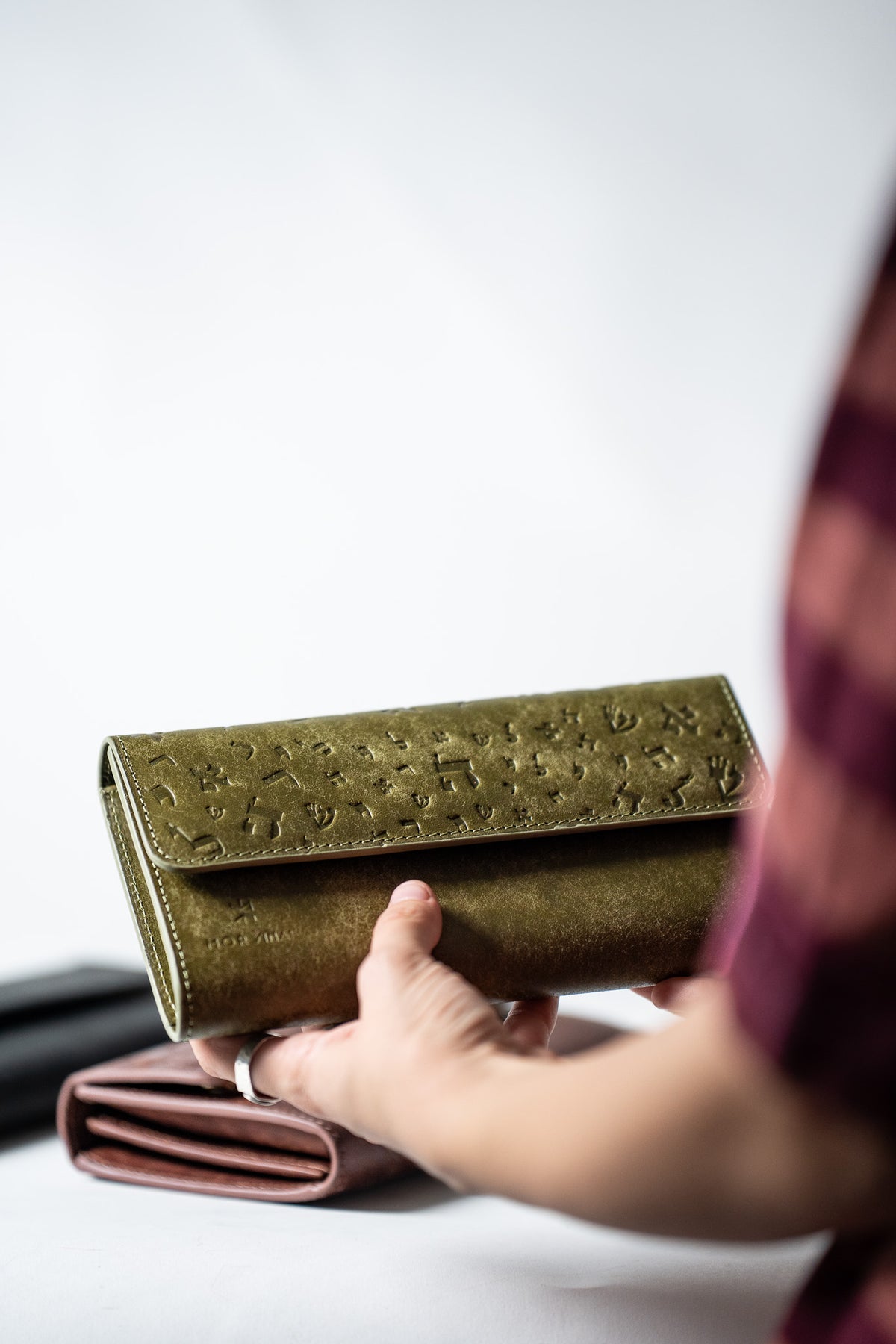 Green leather ladies wallet held in a hand, side view