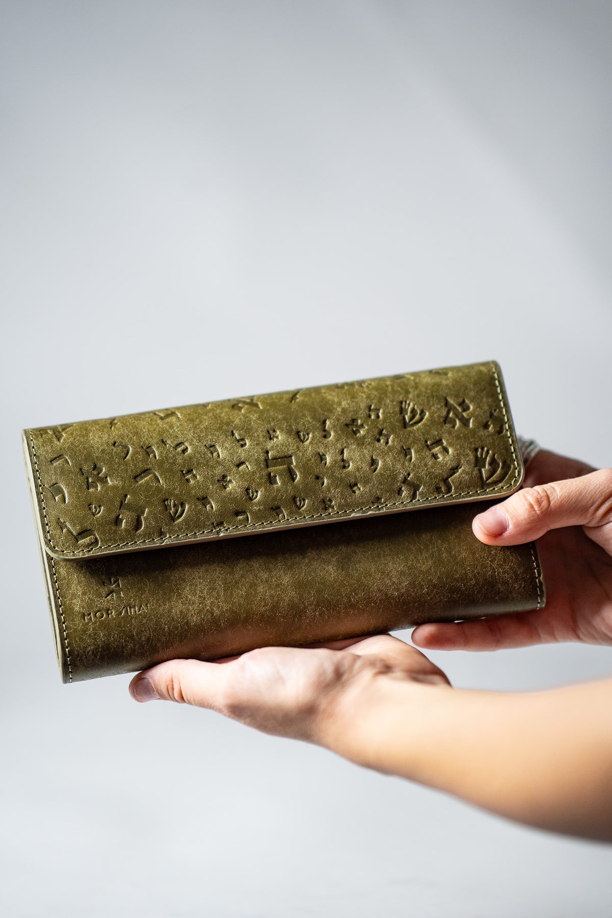 Green leather ladies wallet held in a hand, angled view