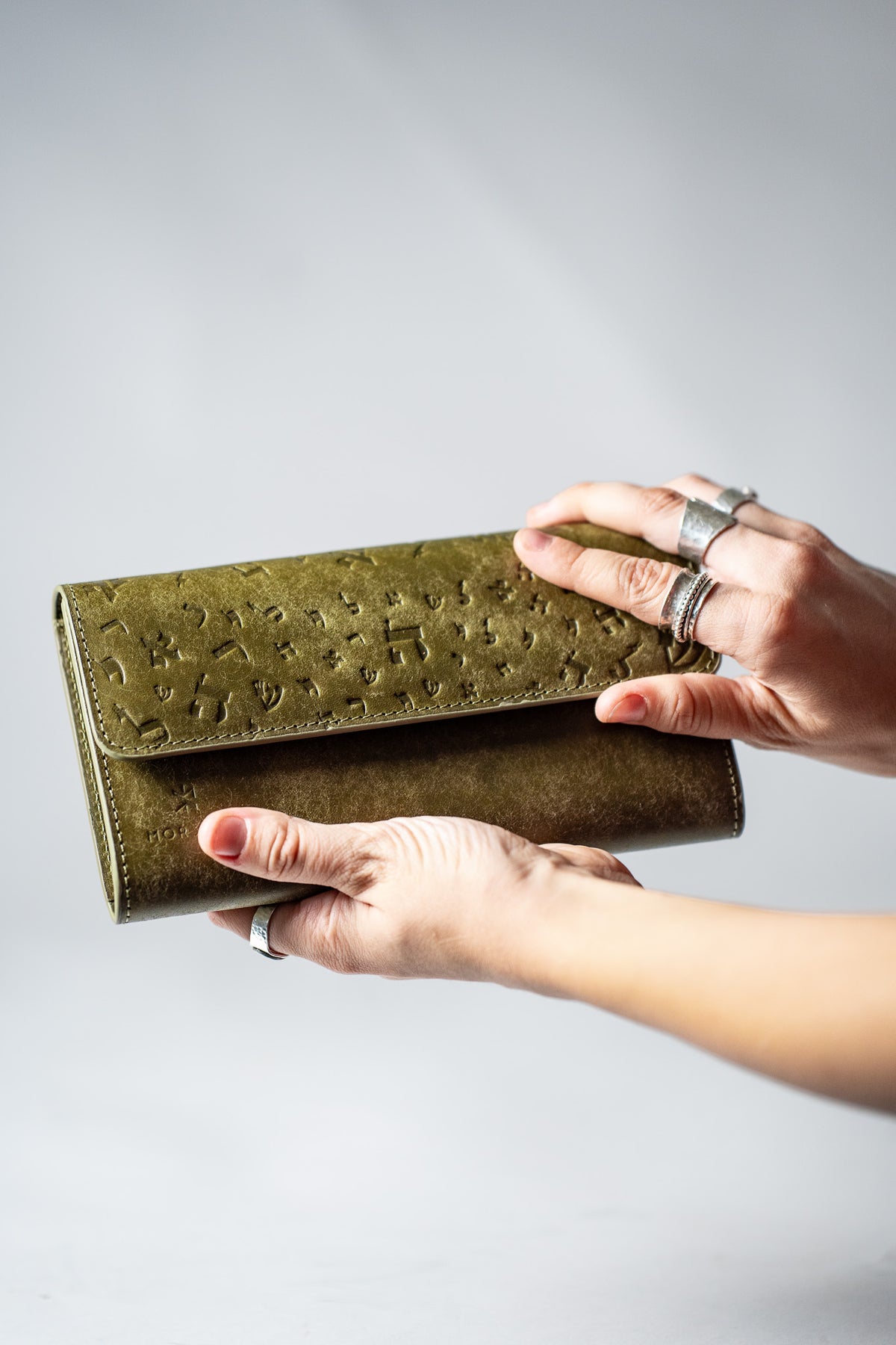 Hand holding the green leather wallet partly open
