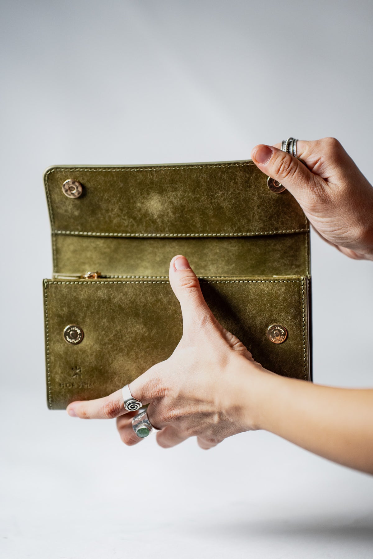 Hands opening the green leather ladies wallet with a magnetic clasp