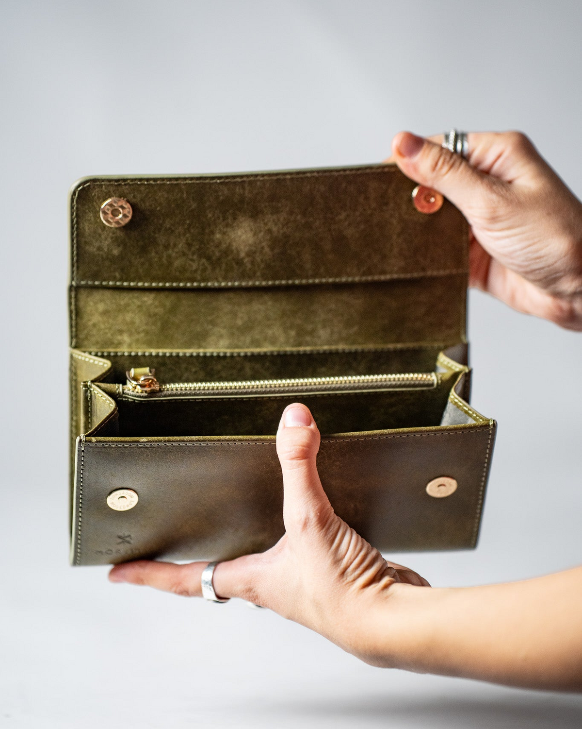 Hands opening the green leather ladies wallet to show the interior