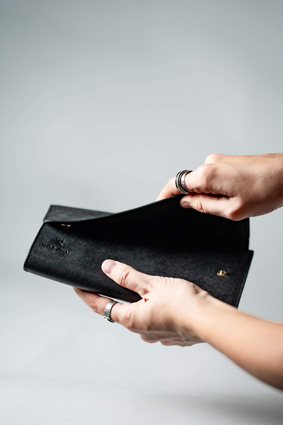 Hands opening the black leather ladies wallet, side view