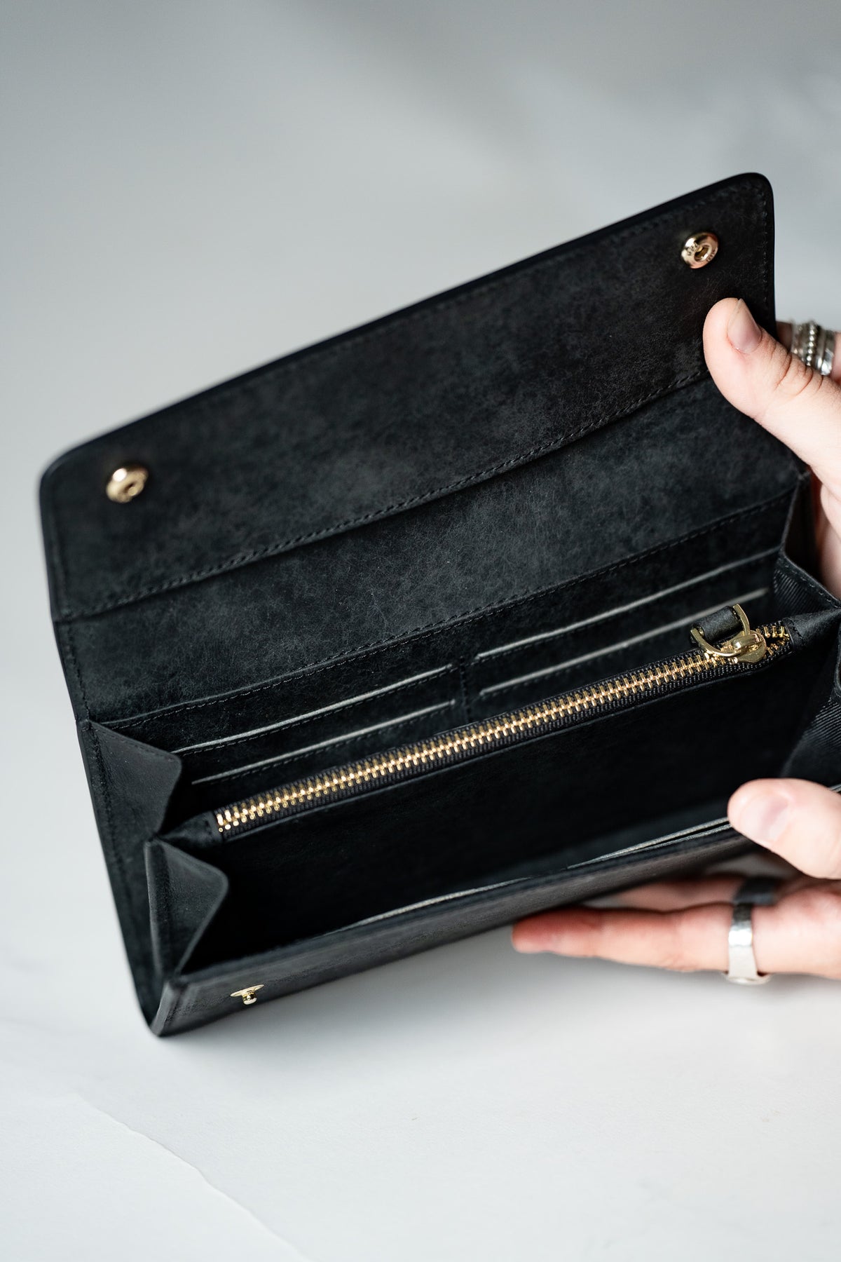 Hands holding the black leather ladies wallet open to show the card slots
