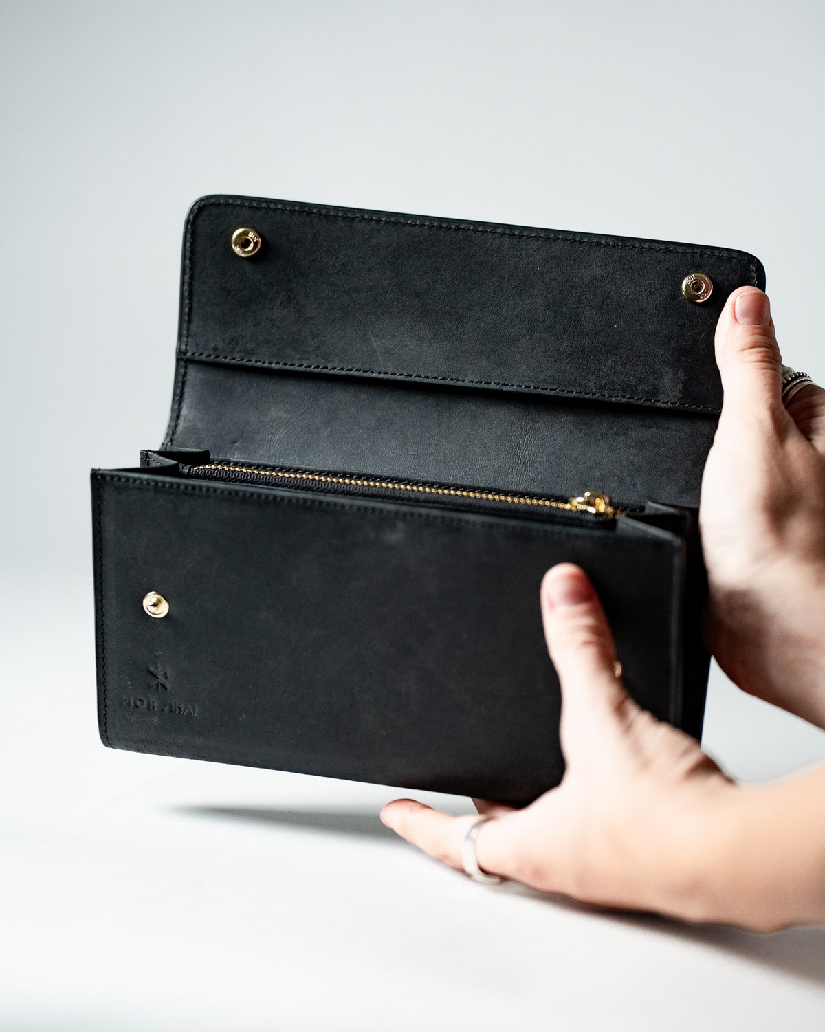 Hands holding the black leather wallet open to show the interior