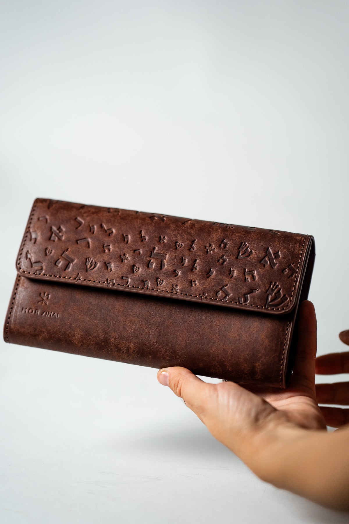Brown embossed leather ladies wallet held in a hand