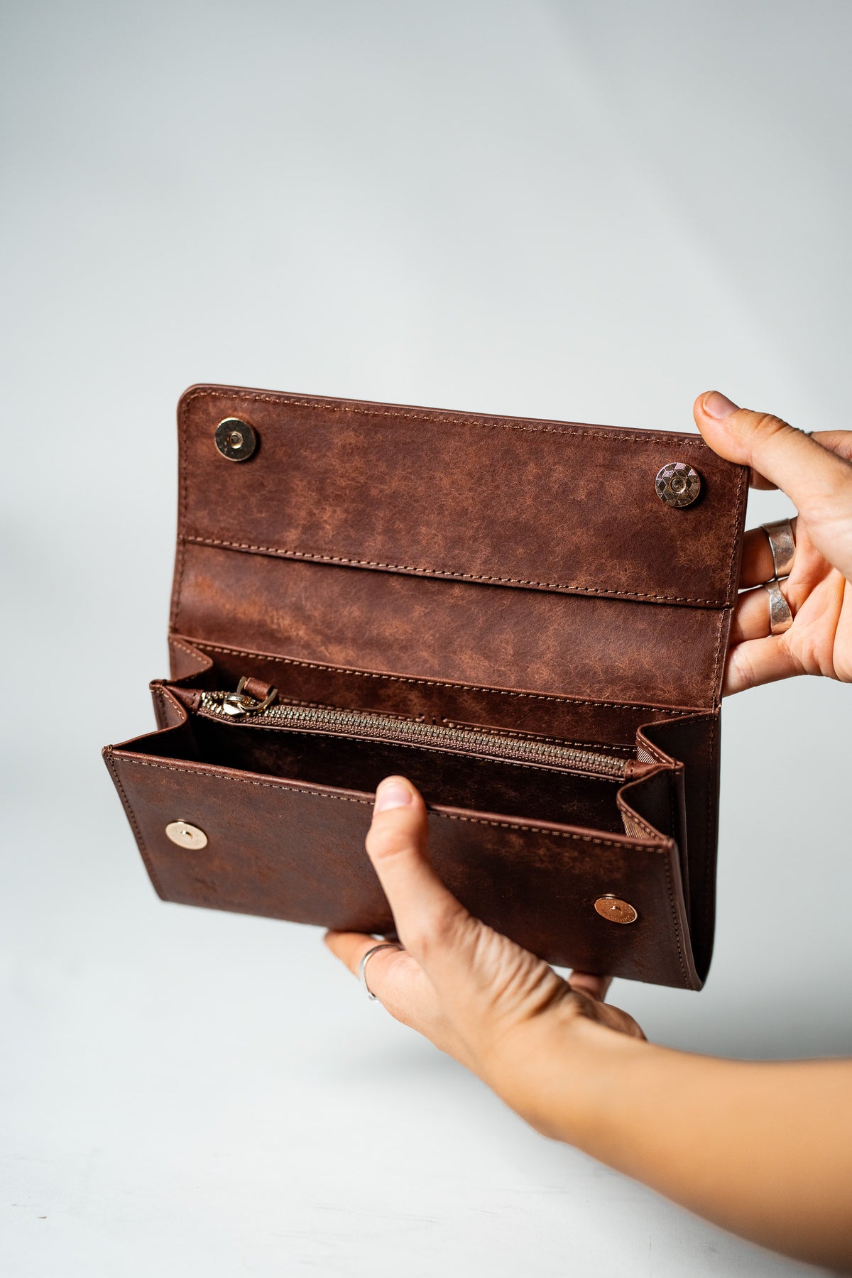 Hand holding the brown leather wallet open