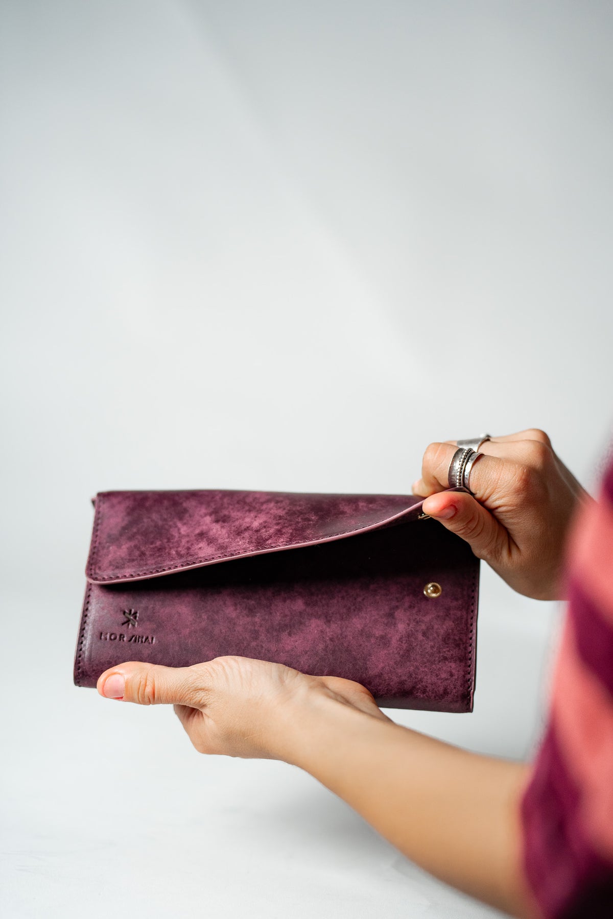 Burgundy leather ladies wallet being opened by a hand