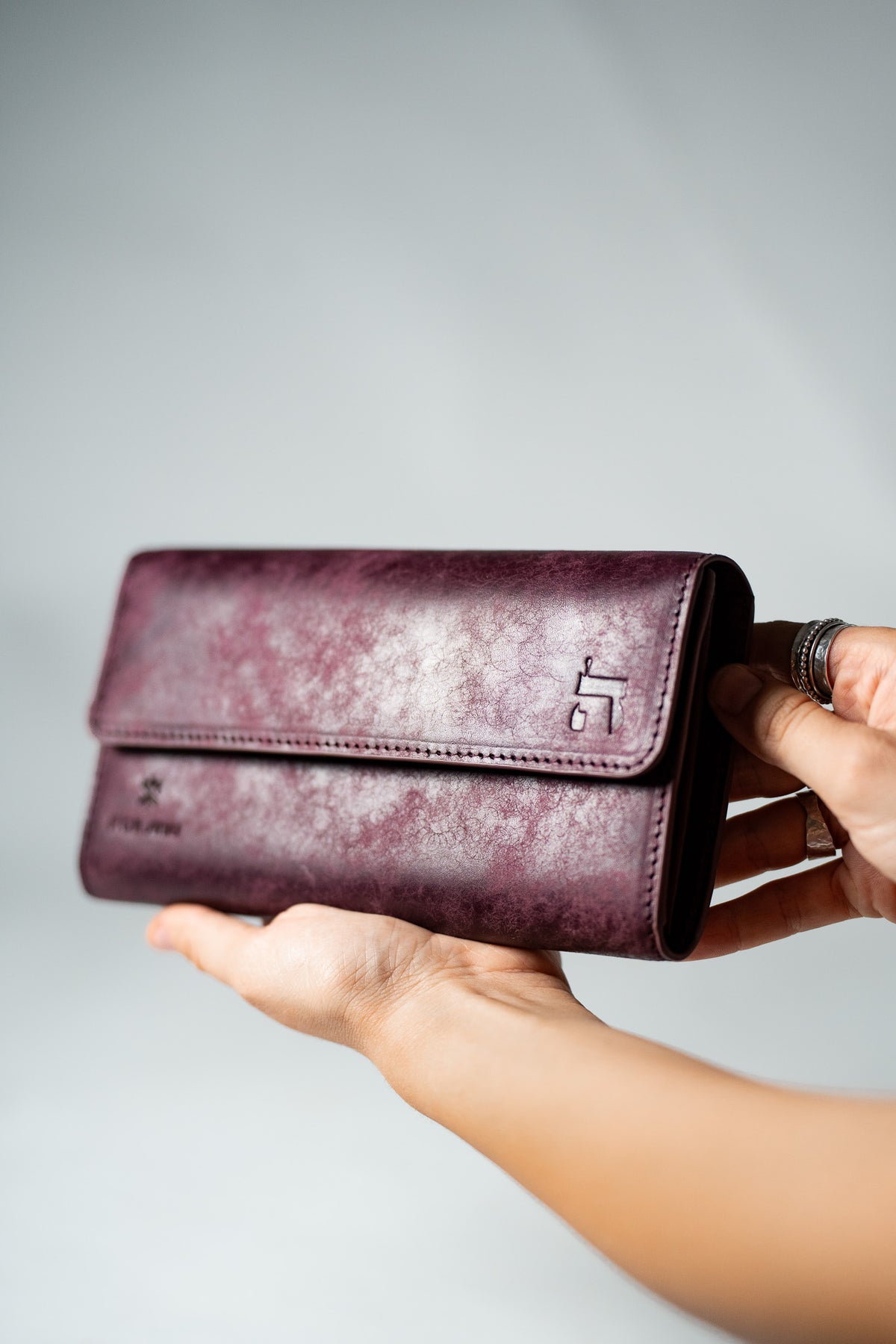 Burgundy leather ladies wallet held in a hand, three quarter view