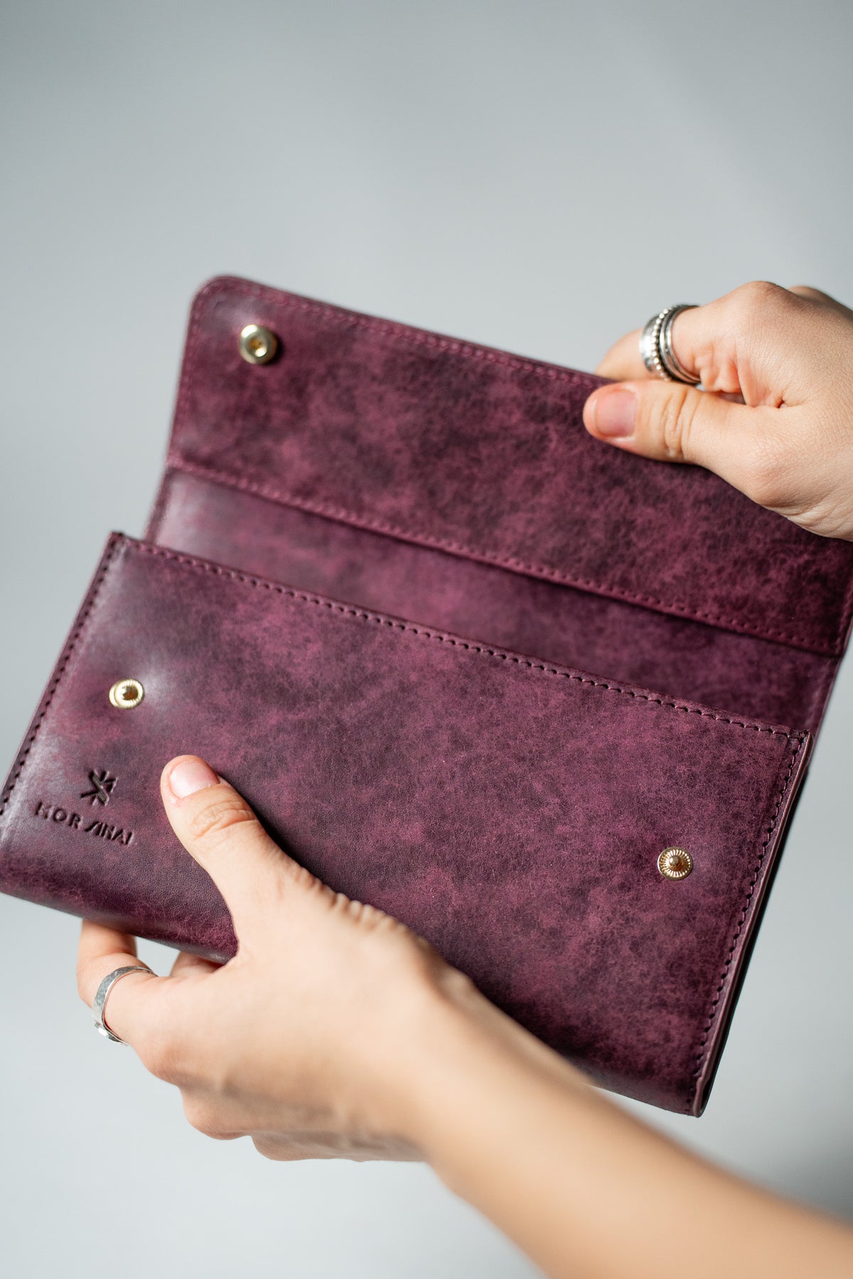 Hand holding the burgundy leather wallet at an angle