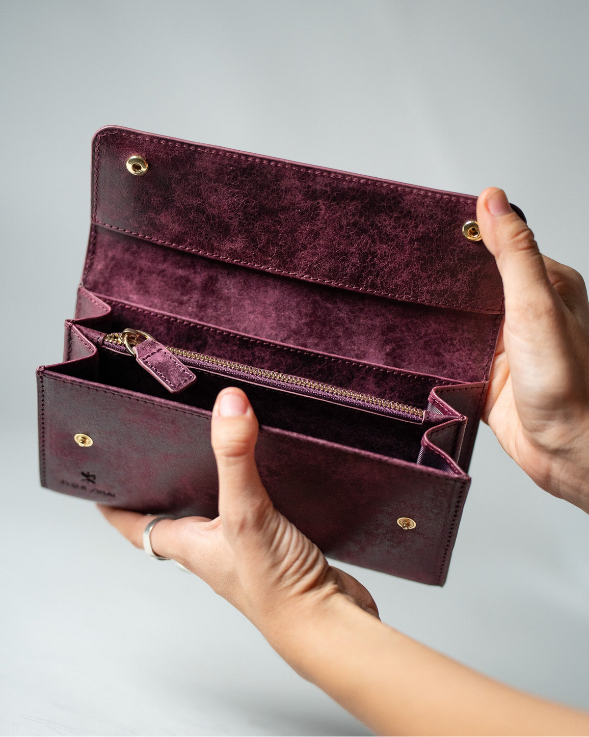 Burgundy leather ladies wallet opened by hands to show the interior