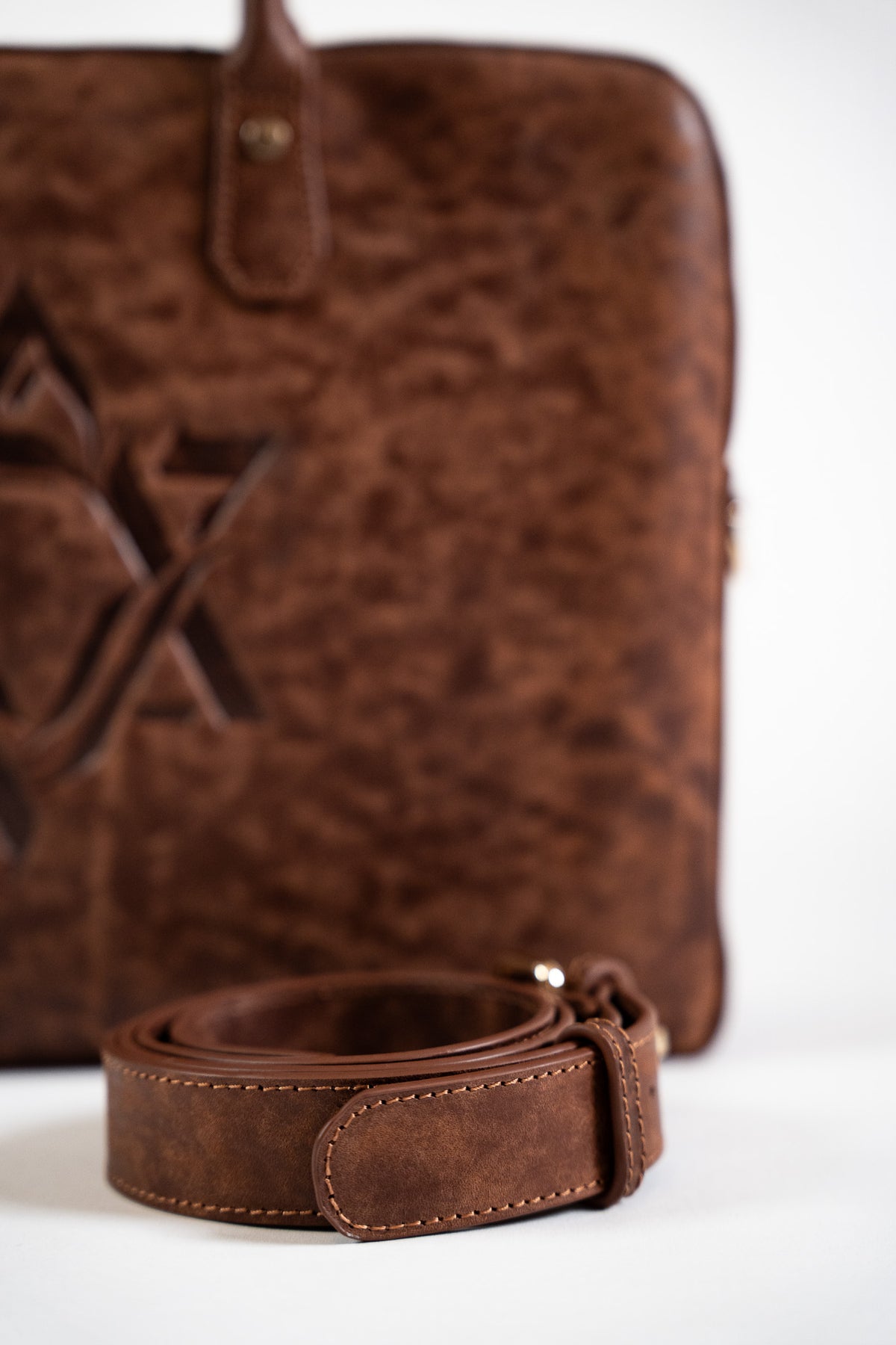 Close-up of embossed Magen David on textured brown leather with a strap